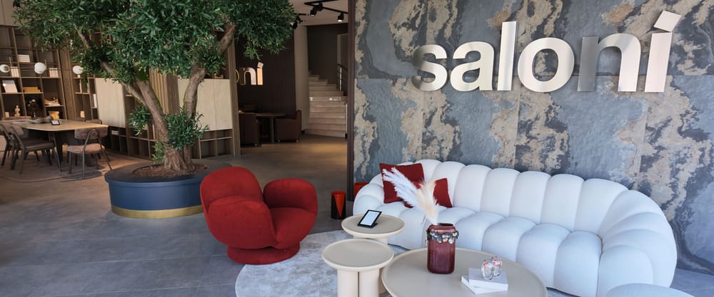 Saloni showroom'unda zeytin ağacının yanında kırmızı koltuk ve beyaz oturma grubu